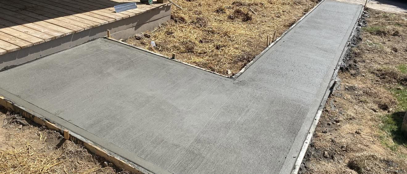 Freshly poured L-shaped concrete driveway and walkway extension
