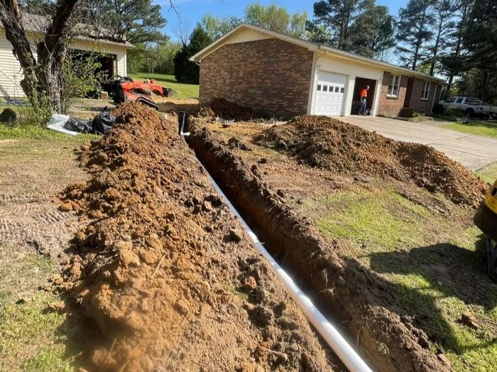 French drain trench and pipe installed alongside a residential driveway