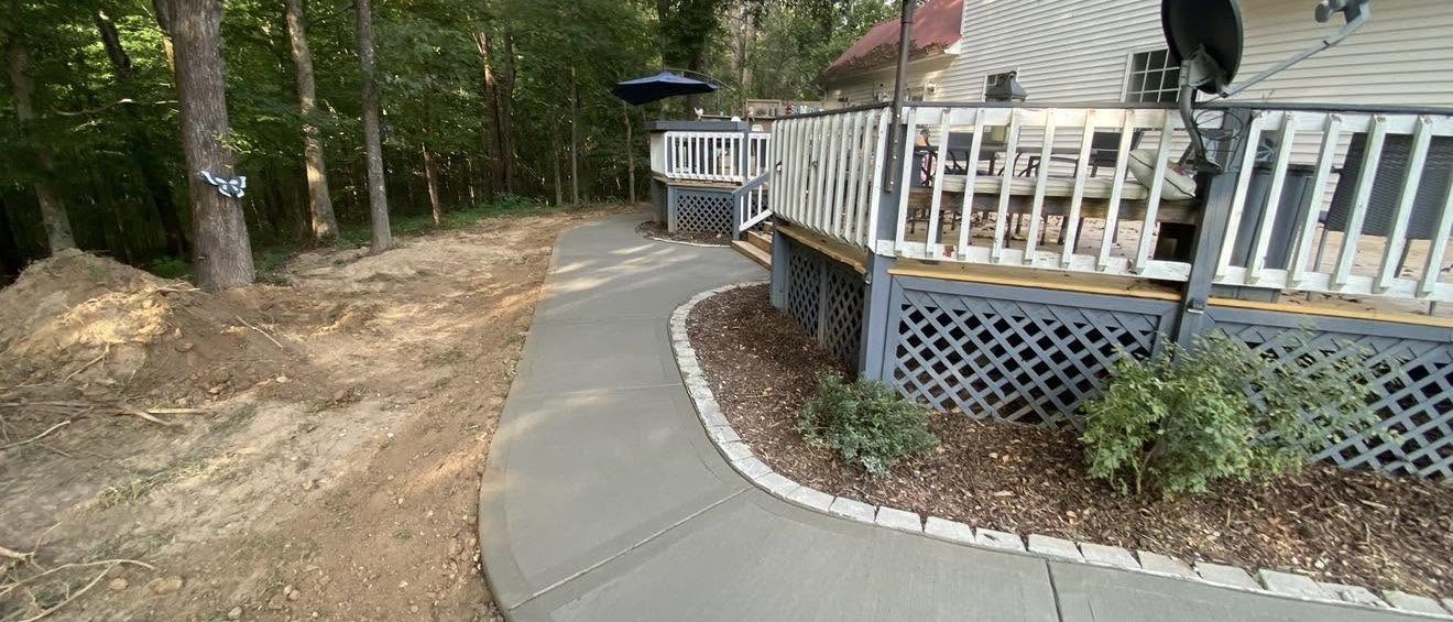 Curved concrete walkway beside a deck with fresh landscaping in Martin, TN