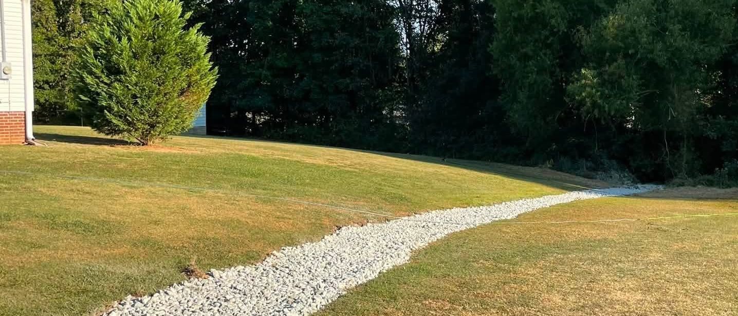 Rock-lined drainage swale directing water away from a home near Mayfield, KY