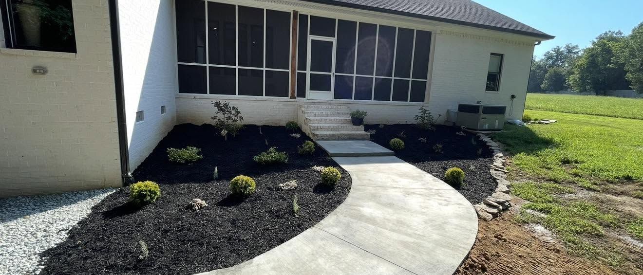 Concrete walkway and mulched planting beds beside a home in Paris, TN